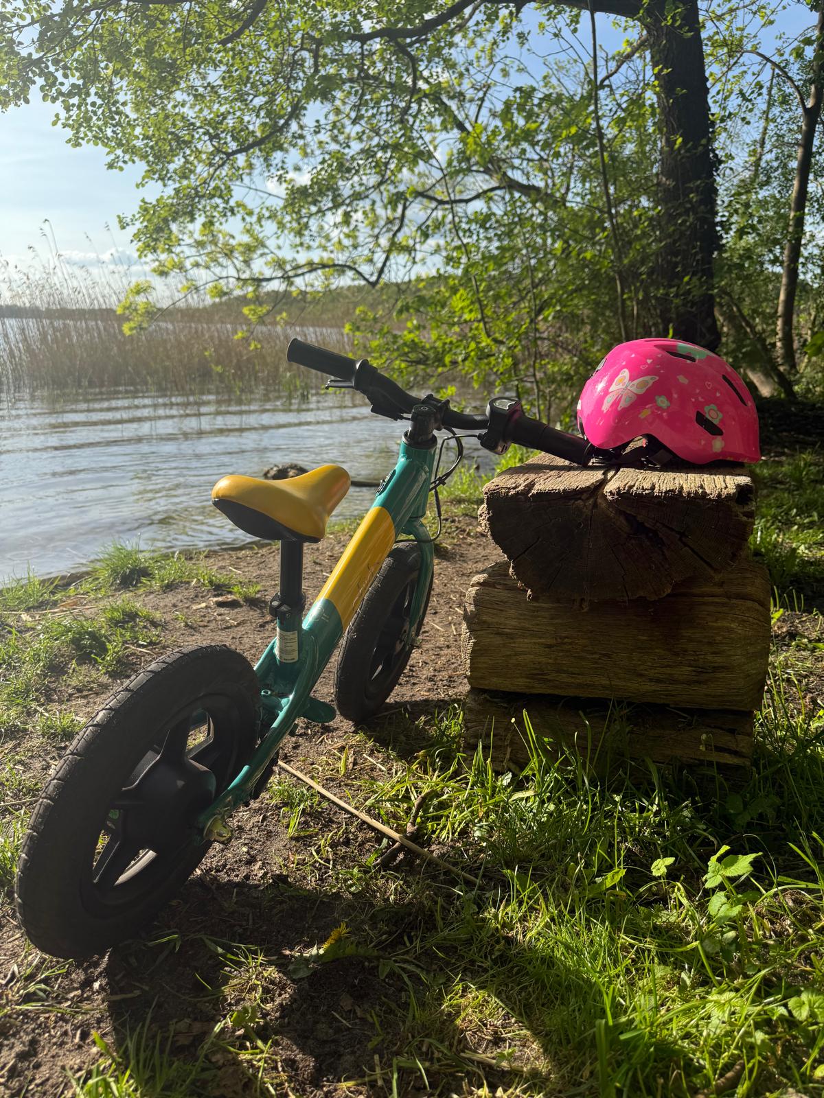 Kleines Fahrrad und Kinderhelm bei einer Pause am sonnigen Seeufer
