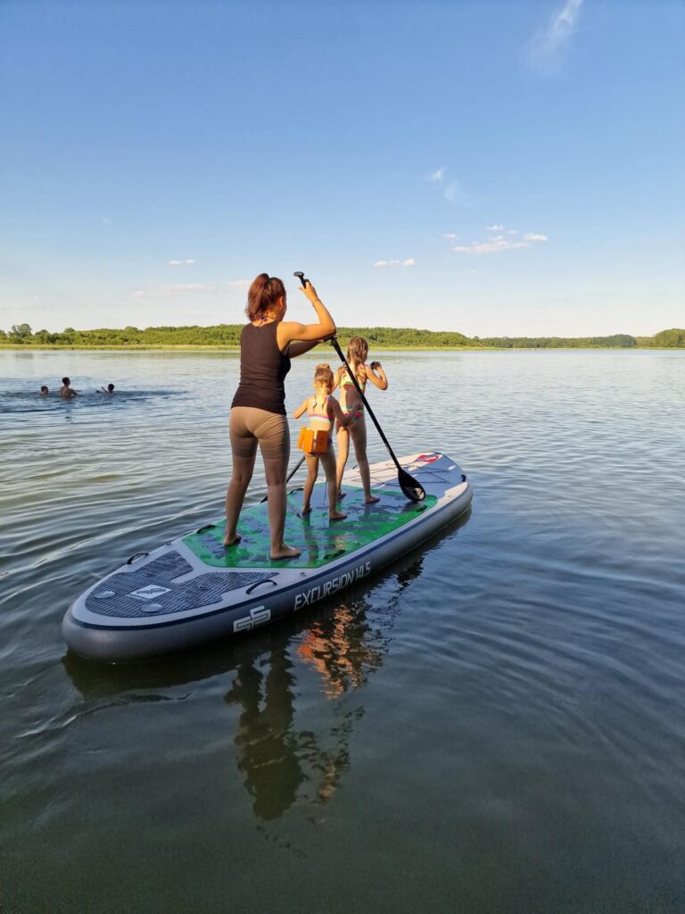 Frau paddelt mit Kindern auf Wasser