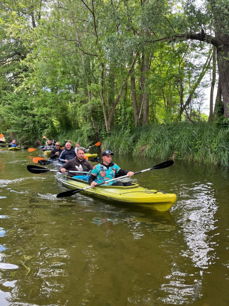 Gemeinsame Kajaktour durch einen grünen Wasserlauf